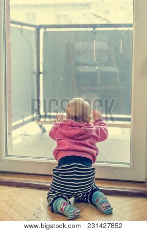 Baby Girl Looking Through Balcony. Leaning On Glass And Exploring.