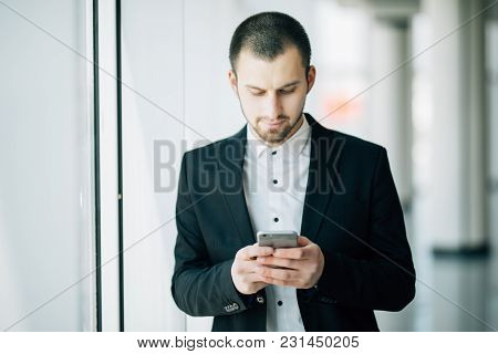 Happy Businessman Reading Text Message On Cell Phone At Office