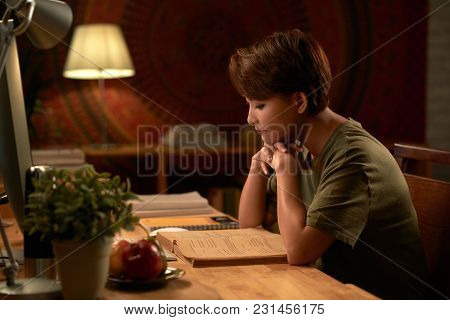Asian Young Woman Reading Students Book At Her Table At Home