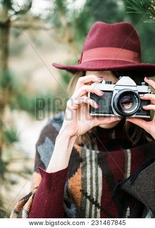 Young Woman Photographing In A Forest Holding A Vintage Camera. Kinfolk / Outdoors Style.