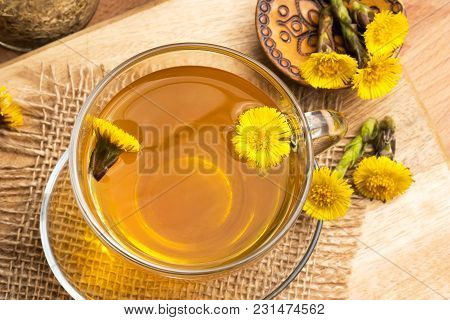 Coltsfoot (tussilago Farfara) Tea With Coltsfoot Flowers On A Wooden Table