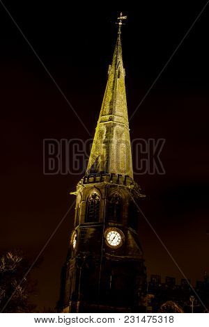 The Church Spire And Clock Lit Up At Night Time