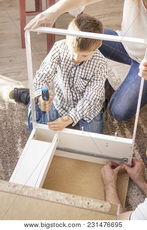 The Mother, With His Son Twist Furniture. The Boy Is Holding A Screwdriver And The Mother Helps To S
