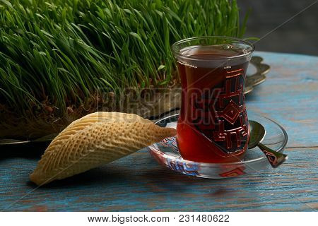 Glass Of Tea With Azerbaijan Pastry Shekerbura And Wheat Grass Semeni On Blue Wooden Table Backgroun