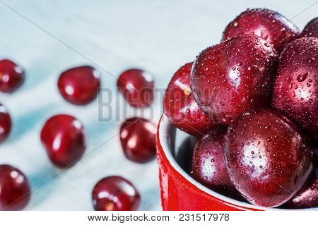 Ripe Cherry Fruits In Old Style In The Red Circle, On White Wooden Table