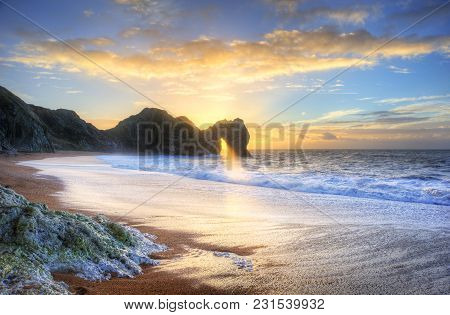 Landscape Image Of Sunrise Shining Through The Arch Of Durdle Door On The Jurassic Coast