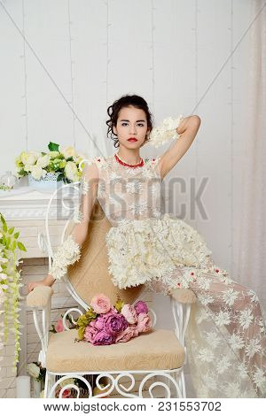 Beautiful Asian Girl In Underwear Posing In Studio On A Vintage Chair With A Bouquet Of Flowers And 