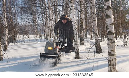 Man In Winter Clothes Fast Riding On Mini Snowmobile On Deep Snowdrifts In The Forest And Maneuverin