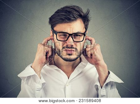 Annoyed Man Looking Grumpy Plugging With Fingers Ears Unwilling To Listen To Anyone.