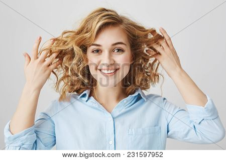 Close-up Portrait Of Playful Attractive Woman With Frizzle Hairstyle Holding Her Curly Hair And Smil