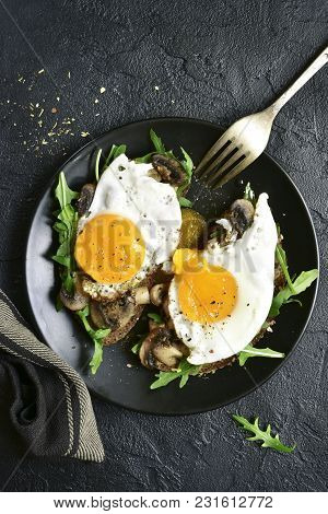 Whole Grain Toasts With Sauteed Mushrooms, Fried Eggs And Arugula Leaves.top View With Copy Space.