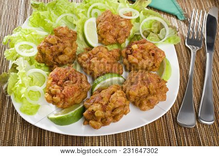 Favourite Indian Appetizer, Indian Bhajias Or Bhajis, On A White Plate With Sliced Lime And Lettuce.