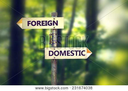 Signpost In A Park With Arrows Pointing In Two Opposite Directions Foreign And Domestic