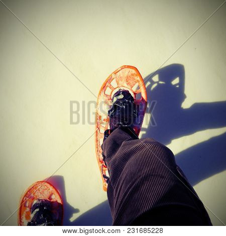 Two Legs Of A Young Man That Walks With Snowshoes With Vintage Effect