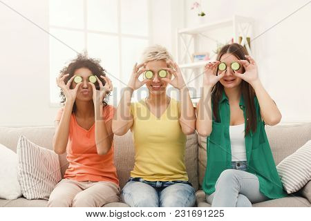 Three Beautiful Girls In Colourful Clothes Having Fun, Covering Eyes With Cucumber Pieces