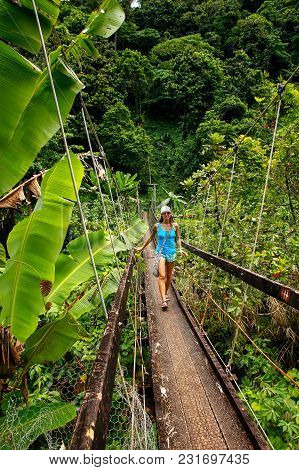 Young Woman Walking On Suspension Bridge Over Wainibau Stream, Lavena Coastal Walk, Taveuni Island, 