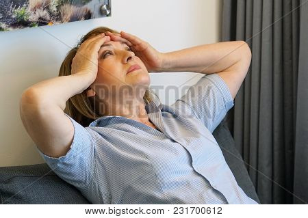 Loss Of A Loved One. Sadly Depressed Elderly Woman At Home, Sitting On The Couch. A Very Unhappy Wom