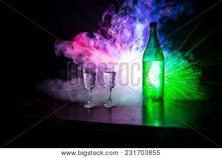 Two Glasses Of Vodka With Bottle On Dark Foggy Club Style Background With Glowing Lights (laser, Sto