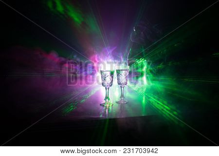Two Glasses Of Vodka With Bottle On Dark Foggy Club Style Background With Glowing Lights (laser, Sto
