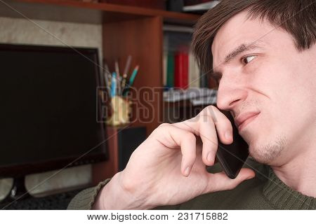 Young Guy Talking On A Black Smartphone With A Smile