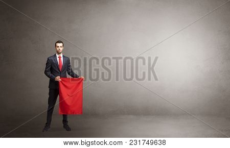 Businessman standing with red toreador cloth in his hand in an empty room