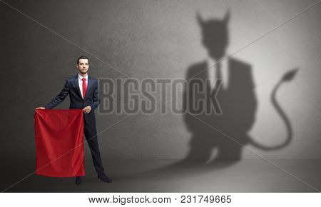 Businessman standing with red cloth in his hand and devil shadow on the background