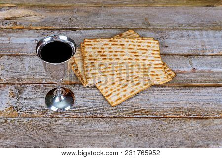 Glass Of Passover Wine And Matzah Close Up. Backlit Blurred Matzah Texture In Background.