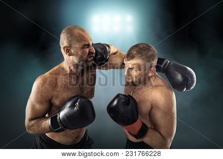 Two professional boxers, athletes in dynamic boxing action on the ring under lights of sport arena.