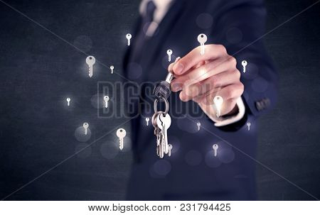 Businessman in suit holding keys with keys graphics around and dark background