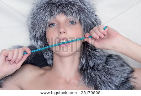 Giovane donna con cappello di pelliccia su sfondo chiaro