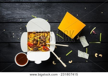 Udon Stir Fry Noodles With Meat And Vegetables In A Box On Black Background. With Chopsticks And Sau