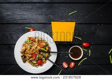 Udon Stir Fry Noodles With Seafood And Vegetables In A White Plate On Black Wooden Background. With 
