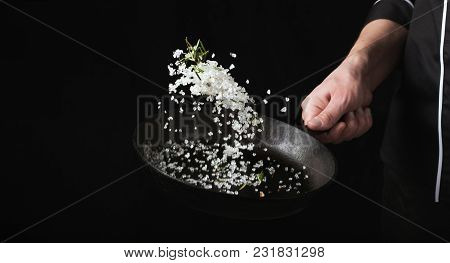 Cooking Roasted Aromatic Salt In A Pan By Chef Hand. Horizontal Photo View. Dark Black Background Wi