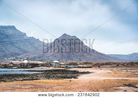Mysterious Landscape Of Sandy Coastline With Fisher Village And Black Volcanic Mountains In Backgrou