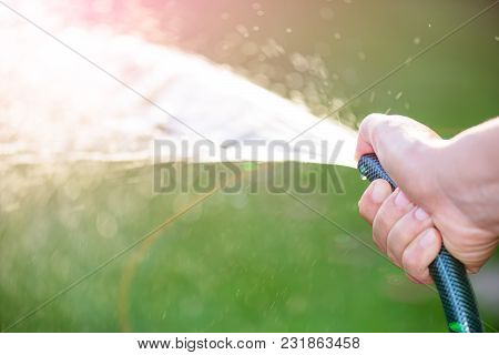 Woman Hand Holding Rubber Water Hose And Using Finger Close End Of Rubber Water Hose To Make  Water 