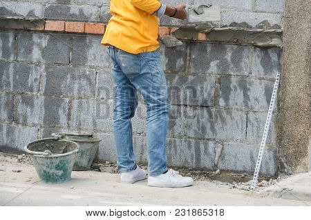 Construction Workers Masons Are Building The Wall From Concrete Blocks.