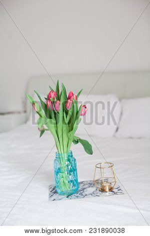 Home Interior. Bedroom. A Bouquet Of Tulips In A Glass Vase, A Candle, A Tray, A Box With A Gift Sta