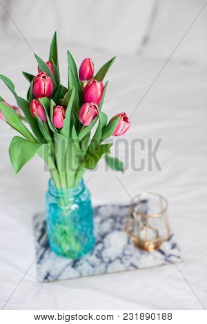 Home Interior. Bedroom. A Bouquet Of Tulips In A Glass Vase, A Candle, A Tray, A Box With A Gift Sta