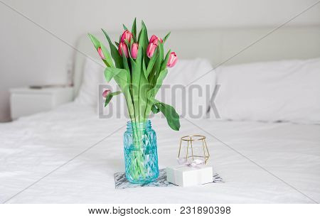 Home Interior. Bedroom. A Bouquet Of Tulips In A Glass Vase, A Candle, A Tray, A Box With A Gift Sta