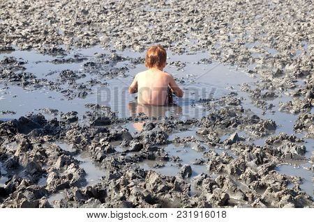 Deposits Of Natural Grey Healing Clay. The Child Gladly Accepts Mud Baths.