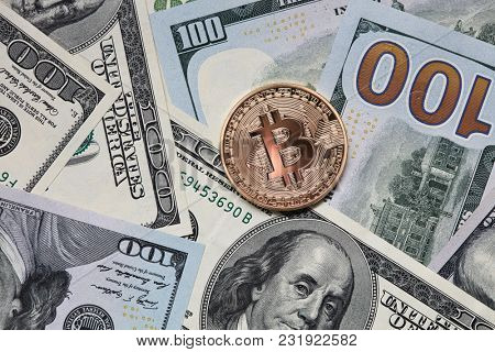 Gold coin bitcoin on the background of hundred dollar bills