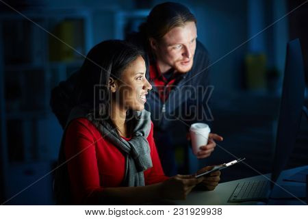 Businesspeople working in team till night. They are using computer for work