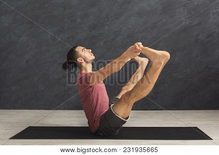 Young Man Practicing Yoga With Gymnastic Mat, Making Corner Stretching Exercise, Copy Space