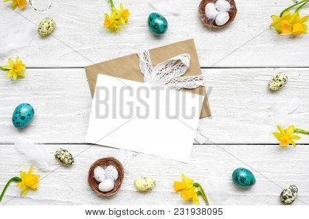 Easter Greeting Card In Frame Made Of Quail Eggs, Spring Flowers And Feathers On White Wooden Backgr