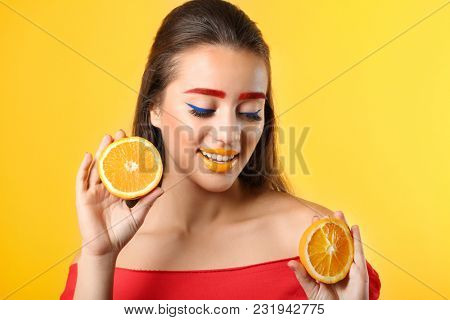 Young woman with dyed eyebrows and halves of orange on color background