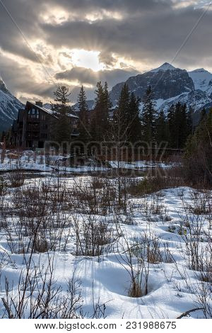 Sunset Along Spring Creek In The Rocky Mountains In Canmore, Alberta With Snow, A Bridge, Trees, And