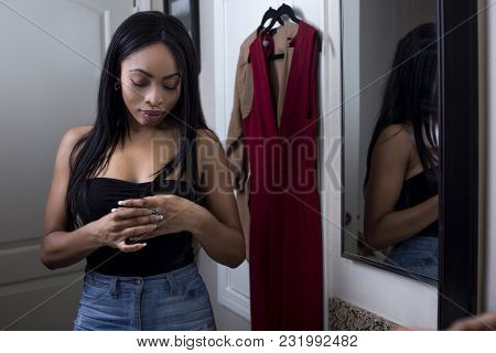 Pretty Black Female Getting Ready In Front Of A Bathroom Mirror Putting On A Ring And Jewelry.  She 