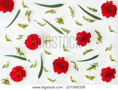 Floral Pattern Made Of Red Carnations, Green Leaves, Branches On White Background. Flat Lay, Top Vie