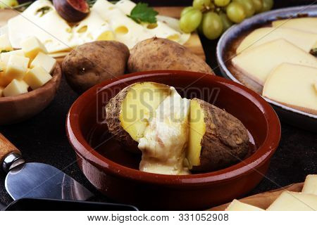 Raclette Cheese Melting On Potato Served In Individual Skillets. Swiss Raclette