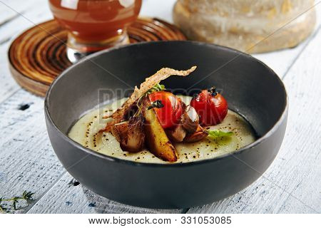 Restaurant Soup Food - Delicious Mushroom Soup with Garlic and Cherry Tomato. Gourmet Restaurant Soup Menu. Mushrooms Soup Garnished with Tea Broth and Garlic Mousse